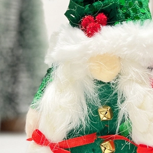 Detail of Christmas gnome with green sequin hat, white faux fur beard and gold bells