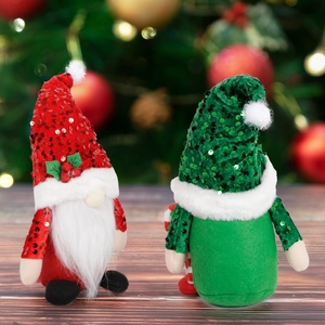 Red and green Christmas gnomes with sequined hats and white beards on wooden table