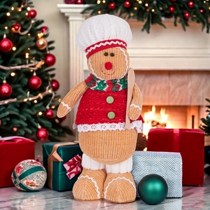 Gingerbread man chef plush with red sweater and white hat standing by a Christmas tree