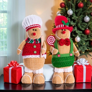 Detail of knitted gingerbread man figurines in chef and gentleman outfits with Christmas tree