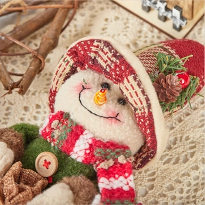 Christmas snowman plush ornament with plaid hat and berry accents on a warm background