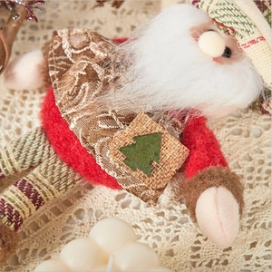 Detail shot of a burlap Santa figurine with felt embroidery on a lace tablecloth