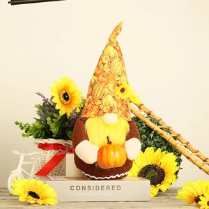 Detail of harvest gnome doll with yellow beard holding orange pumpkin on decorative stand