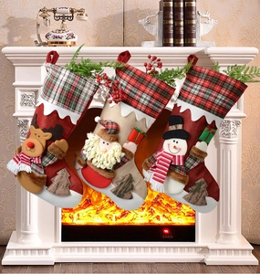Détail de chaussettes de Noël avec renne, Père Noël et bonhomme de neige suspendues au foyer