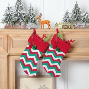 Détail de chaussettes de Noël en tricot avec motifs ondulés, pompons et verdure
