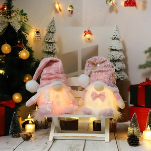 Pair of pink LED Christmas gnomes with knit and sequin hats on a white bench décor
