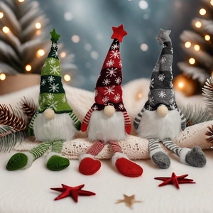 Three Christmas gnomes with striped legs sitting on white blanket under warm festive lights