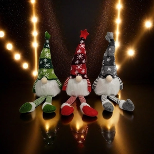 Three Christmas gnomes with knit snowflake hats and striped long legs on reflective surface