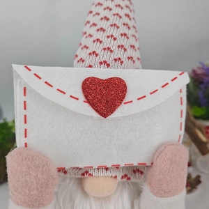 Plush gnome holding a white felt envelope with a red glitter heart for Valentine decorations