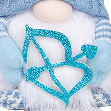 Detalle de un gnomo de peluche con un arco y una flecha de purpurina con corazón