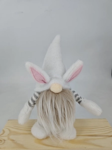 Detail of Easter gnome plush with pink bunny ears and soft grey beard on wood base