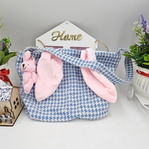 Blue houndstooth Easter basket with pink bunny ears and plush charm on white background