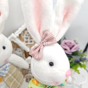 Detailed view of plush Easter bunny doll with pink bow and floral background decoration