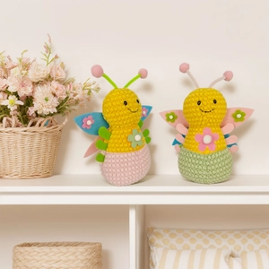 Handcrafted knitted plush honeybee and butterfly toys on a cozy white wooden shelf