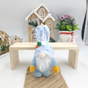 Dettaglio dello gnomo pasquale di peluche con orecchie da coniglio e guanti gialli vivaci
