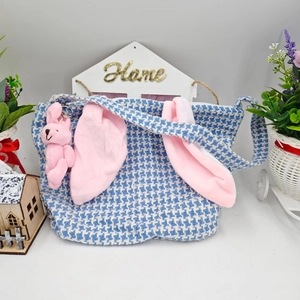 Detail of blue houndstooth Easter bag featuring pink bunny ears and plush charm