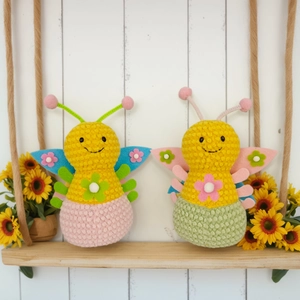 Two handmade crochet bee plush dolls on a wooden swing with sunflower decorations