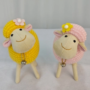 Dettaglio di pecorelle di peluche fatte a mano all'uncinetto in rosa e giallo con campanelli