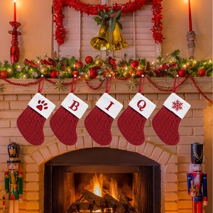 Set of five red knit Christmas stockings with white faux fur cuffs by a cozy fireplace