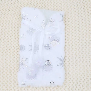 Close-up of white plush Christmas wine bottle cover with silver snowflakes and bow