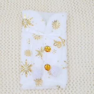 Close-up of a white faux fur wine bottle cover featuring gold snowflakes and amber buttons