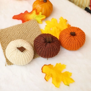 Three handmade knitted pumpkins in orange, cream, and red for autumn harvest decoration