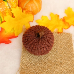 Macro detail of brown knitted pumpkin ornament with texture on rustic burlap surface