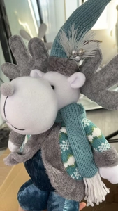 Detail of Christmas reindeer plush with blue knitted hat and snowflake pattern coat