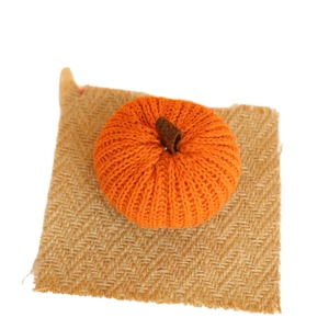Handmade orange knitted pumpkin decor on burlap mat for harvest festival and thanksgiving