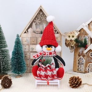 Charming Christmas penguin plush doll with a red knit hat on a small white wooden sleigh