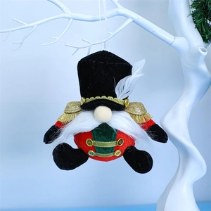 Detail of Nutcracker gnome plush hanging ornament with red and green uniform on white branch