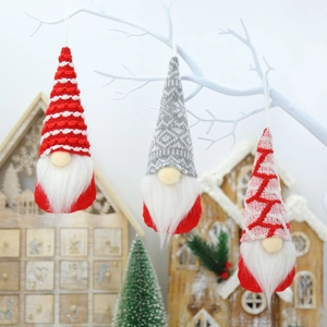 Three plush Christmas gnomes with knitted hats hanging on a festive winter branch decoration