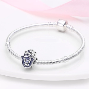 Macro-opname van een Hamsa-handbedel met blauwe zirkoon op een zilveren slangenketting armband
