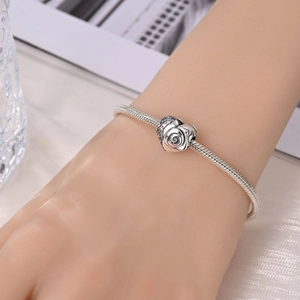 Macro shot of silver-plated snake chain bracelet with rose charm worn on a wrist