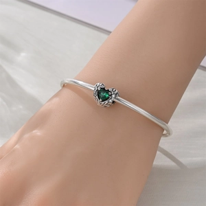 Zilveren armband met hartvormige groene edelsteen en engelenvleugel details om de pols