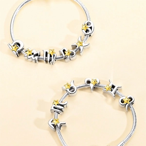 Detail of silver snake chain bracelet featuring zodiac charm and golden star pendant