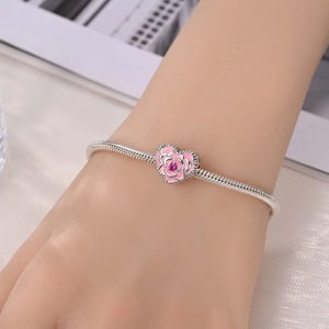 Detail of silver snake chain bracelet with pink rose heart charm and enamel flower