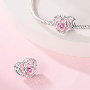 Macro view of heart charm with pink enamel rose and gemstone on silver bracelet