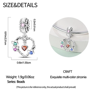 Detail view of heart-shaped charm with colorful zircons and intricate floral engraving