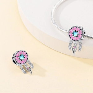 Detailed view of dreamcatcher charm with pink enamel heart and blue iridescent gem
