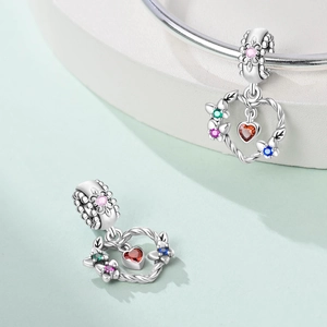 Macro detail of silver heart charm with colorful crystals and floral engraving