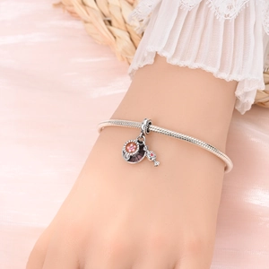 Silbernes Schlangenarmband mit Emaille-Blumenanhängern am zarten Handgelenk