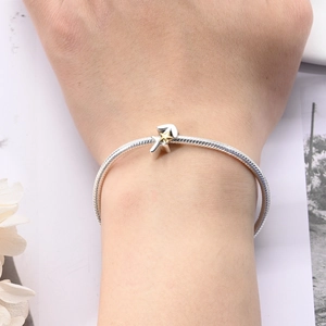 Detail of silver snake chain bracelet with Sagittarius bow and gold star charm