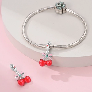 Detail of silver snake chain bracelet with red cherry charm and pink flower clasp