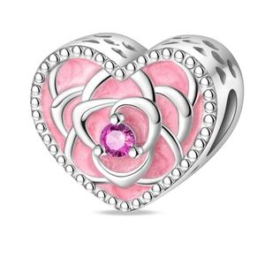 Macro detail of heart charm with pink enamel, silver rose pattern and purple zircon