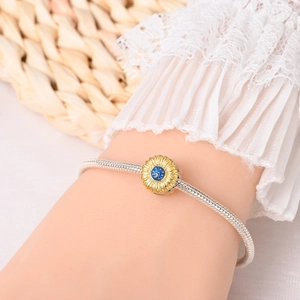 Detailed close-up of a sunflower charm with blue enamel moon and star on a silver bracelet