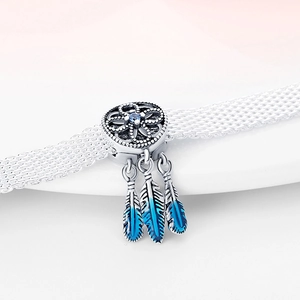 Macro shot of dreamcatcher charm with blue feathers on a silver mesh bracelet