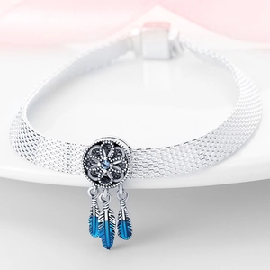 Macro shot of silver dreamcatcher charm bracelet with blue feathers and sparkling zircon
