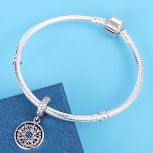 Detail van de zilveren slangenarmband met zonne-hanger en blauwe kristallen bedeltje
