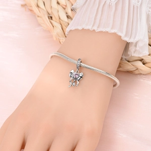 Detail of silver bow charm with a pink heart-shaped stone on a snake chain bracelet